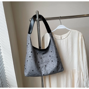 Close-up of star pattern canvas tote bag with black leather handle on display