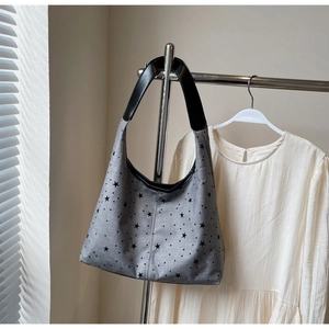 Detail of grey canvas hobo bag with black star patterns and leather shoulder strap