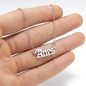 Detailed close-up of a silver Aries zodiac necklace with gothic font lettering