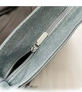 Macro shot of smooth silver metal zipper and blue denim fabric of a crossbody bag