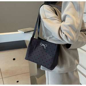 Detail of canvas bucket bag featuring red heart patterns and a white bow decoration