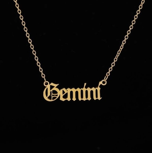 Detailed view of Gemini zodiac pendant in gothic font with golden cross chain