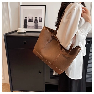 Brown lychee texture leather tote bag on shoulder showing large capacity and seams