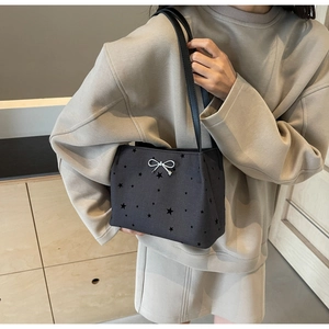 Detail of black canvas bucket bag featuring star patterns and silver bow ornament