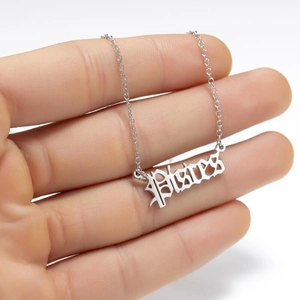 Macro detail of silver Pisces zodiac necklace with Old English gothic font pendant