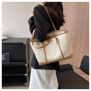 Detail of white lychee pattern tote bag with brown straps worn over the shoulder