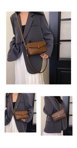 Detail of a brown leather crossbody bag featuring a golden metal buckle and chain strap