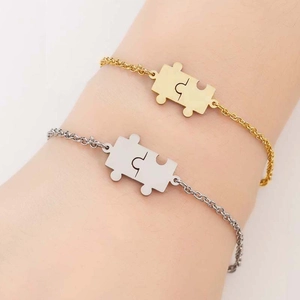 Close-up of interlocking puzzle pendants on gold and silver chain bracelets for couples