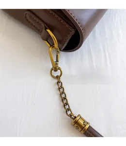 Détail des crochets dorés mats et de la bandoulière chaîne d'un sac bandoulière marron