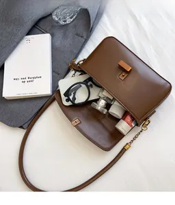 Sac bandoulière en cuir marron montrant un intérieur spacieux pour le maquillage