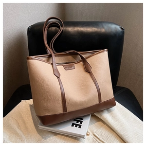 Detail of lychee textured tote bag with contrast brown trim on a classic leather chair