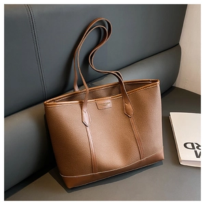 Detail of lychee textured brown tote bag with embossed logo and reinforced stitching