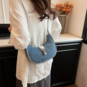Blue denim half-moon underarm bag with silver buckle worn by a model in casual setting