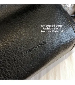 Close-up of the embossed logo and premium lychee grain texture on a black leather tote