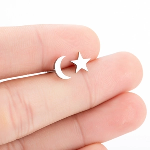Close-up of asymmetric star and moon stainless steel earrings held between fingers