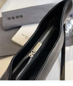 Close-up of black lychee grain leather tote bag with elegant silver metal zipper detail