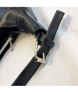 Detailed macro view of adjustable leather shoulder strap with silver metal buckle on black tote