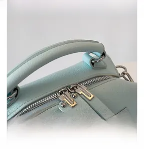 Detail showing mint green lychee grain leather handle and silver metal zipper on the bag
