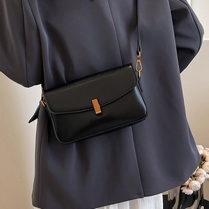 Retro black minimalist crossbody bag with gold rectangular clasp on grey blazer outfit