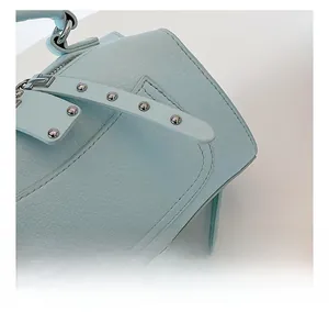 Close-up of light blue leather handbag showing lychee texture and silver metal rivets