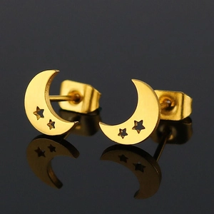 Detail showing golden crescent moon earrings with star cutouts on a reflective surface