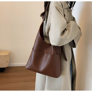 Détail d'un sac hobo en cuir marron avec poches frontales porté par un mannequin