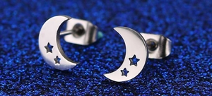 Macro shot of silver crescent moon stud earrings with hollow star cutouts on blue glitter