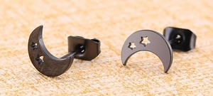 Macro shot of black moon stud earrings with hollow stars and polished steel finish