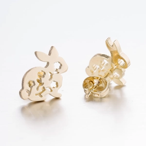 Close-up of golden rabbit stud earrings with hollow floral pattern and butterfly backings