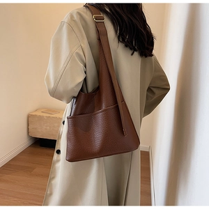 Détail de la boucle dorée ajustable et du cuir grainé marron sur le grand sac à main