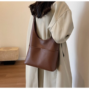 Détail de la texture en cuir marron d'un sac seau avec de grandes poches extérieures