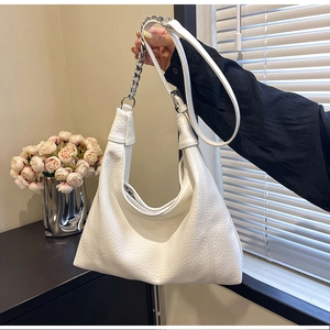 Detail of white lychee leather hobo bag with silver chain strap in natural setting