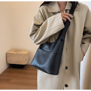 Détail d'un sac seau en cuir grainé noir avec coutures verticales et bandoulière réglable