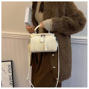 Detail of off-white leather handbag with top handle and stylish rivet pocket design