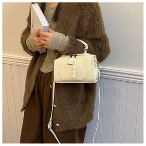 Detail of cream mini crossbody bag showing smooth faux leather texture and metallic studs
