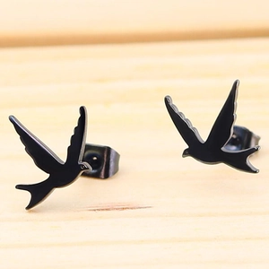 Minimalist matte black swallow bird stud earrings in stainless steel on wood