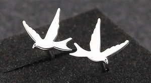 Macro shot of silver bird-shaped stud earrings on a black textured display background