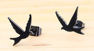 Detail view of black swallow bird stud earrings on wood base showing matte metal finish