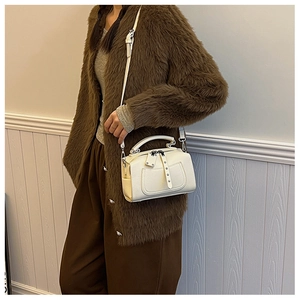 Detail showing the white Boston bag with metal studs and detachable shoulder strap on a model