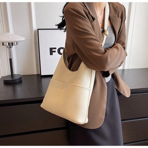 Détail de la texture cuir grainé et boucle métallique sur le sac bandoulière crème