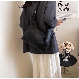 Detail of a black pebbled leather Hobo tote bag shown on a model for daily commuting
