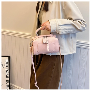 Detail of light pink Boston bag with textured leather, silver zippers and shoulder strap
