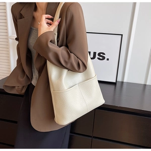 Détail d'un sac cabas en cuir grainé blanc crème porté par un mannequin en intérieur