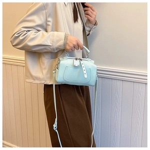 Detail view of mint green handbag featuring double zippers and decorative front pocket rivets