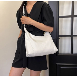Detail of white lychee grain hobo bag with silver chain strap shown on model shoulder