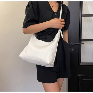 Detailed texture of white lychee leather hobo bag worn by model in black dress