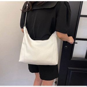 Detail of white leather tote bag with silver metal chain strap and pebble texture