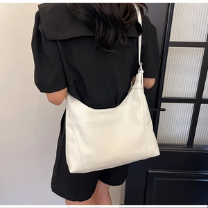 Close-up of minimalist cream white hobo bag with natural soft leather texture and adjustable strap