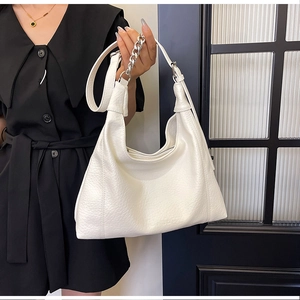 Close-up of white lychee leather tote bag with silver chain strap on model shoulder