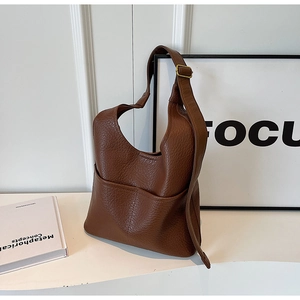 Gros plan sur le sac seau en cuir grainé marron foncé avec boucle en laiton et bandoulière